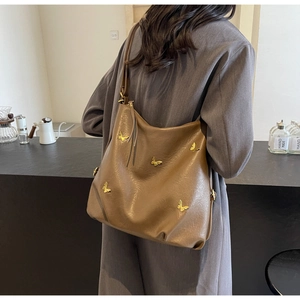 Detail of a brown PU leather tote bag featuring five golden butterfly metal ornaments