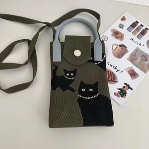 Detail of green knitted crossbody bag featuring black cat designs and pearl accents