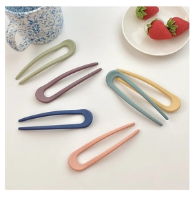 Flat lay of colorful U-shaped matte hair pins in candy colors with ceramic props