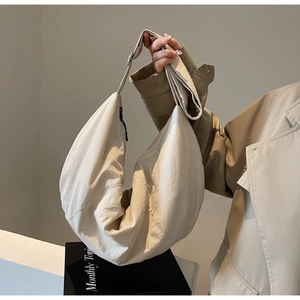 Minimalist beige nylon hobo bag held by a model for a casual and stylish daily look