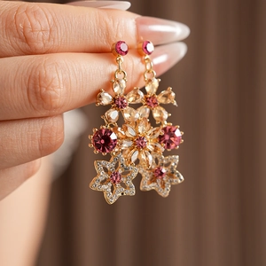 Close-up of vintage floral earrings with pink gems and sparkling star-shaped pendants
