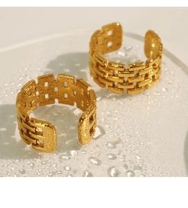 Macro shot of two golden titanium rings with chain texture on a wet reflective surface