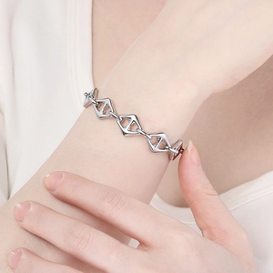 Detailansicht eines silbernen Armbands mit geometrischem Rautenmuster am Handgelenk getragen