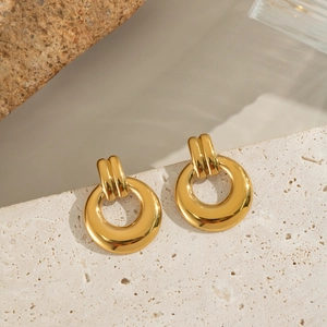 Detailed view of gold geometric double hoop earrings on a textured beige stone base