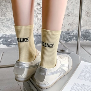 Yellow ribbed mid-calf socks with Good Luck lettering and retro sneakers on a street scene