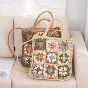 Handmade crochet straw tote bag with colorful granny square patterns on a sofa