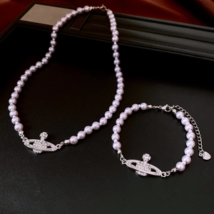 Close-up of pearl necklace and bracelet set with rhinestone Saturn orb and heart charm