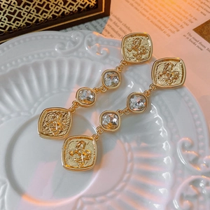 Detail of vintage gold lion relief coin earrings with sparkling crystal tassels on ceramic