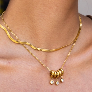 Close-up of layered 18K gold plated stainless steel snake chain and crystal pendant necklace