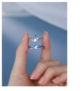 Close-up of adjustable S925 silver couple rings with blue enamel whale tail and wave patterns
