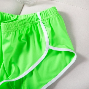 Detailansicht der neongrünen Sport-Shorts mit weißem Saum und elastischem Hosenbund