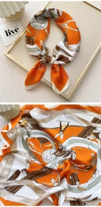 Detail of a square silk scarf with circus print in orange and white within a frame