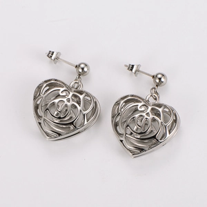 Detailed view of silver hollow heart earrings in polished stainless steel on white