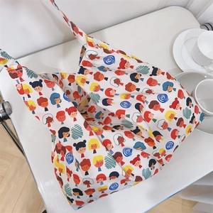 Close-up of white cotton tote bag featuring dense colorful cartoon head prints and soft texture