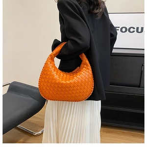 Close-up of orange woven croissant bag with Intrecciato texture for women