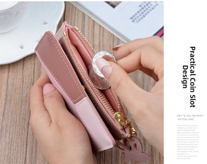 Pink zippered wallet featuring a bunny metal charm and interior coin pocket on desk