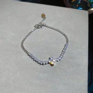 Detail of silver bracelet with marquise-cut stones and a four-petal floral pendant