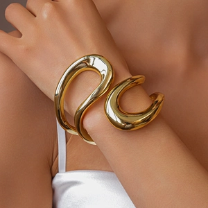 Detailansicht der breiten goldpolierten Manschette mit wellenförmigem Skulpturdesign