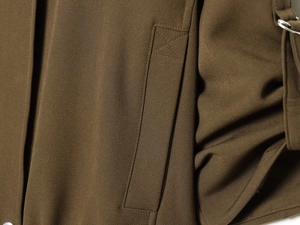 Detailed macro view of khaki bomber jacket stitching with metal D-ring adjustment buckle