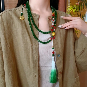 Détail du collier de perles vertes avec de longues franges colorées et détails élégants