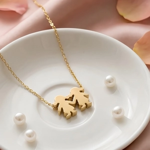 Close-up of gold stainless steel necklace with two girls holding hands heart pendant