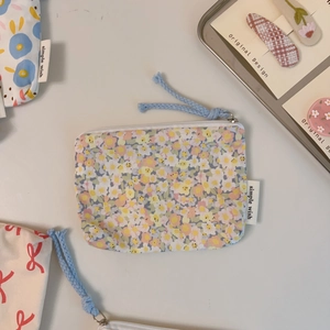 Detailed close-up of floral print cotton mini pouch with zipper and simple wish label