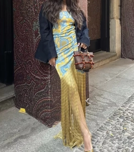 Detail of yellow and blue print maxi dress featuring gold fringe hem and blue blazer