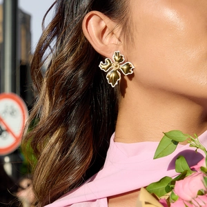 Elegant 18K gold plated stainless steel white flower earrings worn by a model outdoors