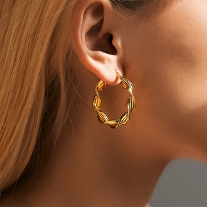 Detail of twisted gold earrings with high-polish finish on model's ear