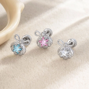 Star-shaped zircon sea shell stud earrings in blue, pink and white on beige velvet