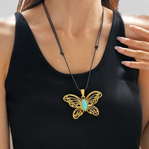 Detail of a filigree golden butterfly pendant with turquoise stone on a black cord
