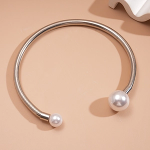 Close-up of silver metal collar necklace with asymmetrical faux pearl ends
