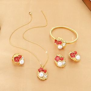 Detailed close-up of gold-plated jewelry set with red enamel flowers and white pearls