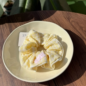 Detail view of yellow and white checkered scrunchie with soft ruffled texture in a bowl