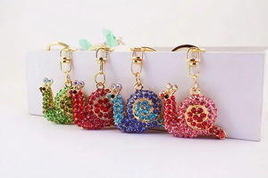 Detailed view of snail keychains with vibrant rhinestones in four elegant colors