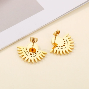 Boucles d'oreilles tournesol dorées en acier inoxydable sur fond minimaliste de crème