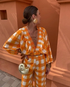 Detail of V-neck puff sleeve crop top with orange checkered pattern and ruching texture