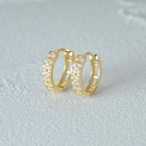 Macro detail of gold S925 sterling silver hoop earrings with pave cubic zirconia stones