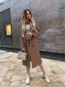 Full-body street view of a camel double-breasted wool coat with notch lapel and flap pockets