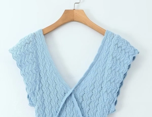 Gros plan détaillé du haut en tricot bleu clair avec col en V et texture au crochet
