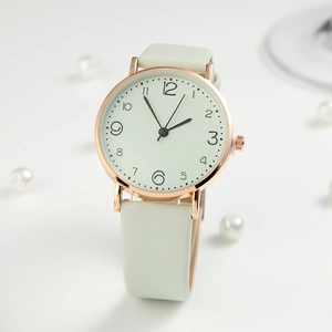 Detailed close-up of a minimalist mint green watch with rose gold case on white background