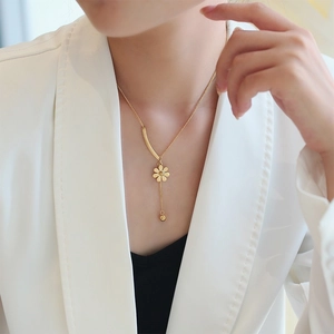 Golden daisy pendant necklace in titanium steel on a model with white suit