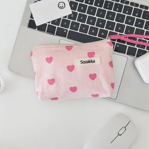 Close-up of pink heart-patterned canvas pouch with zipper on a laptop keyboard