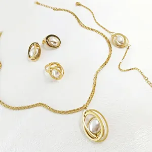 Elegant gold jewelry set with faux pearls featuring layered oval rings on white leather