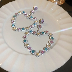 Détail de boucles d'oreilles cœur ajouré avec strass colorés et cristaux brillants