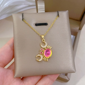 Detailed shot of golden crab necklace featuring a pink gradient gem and crystal accents