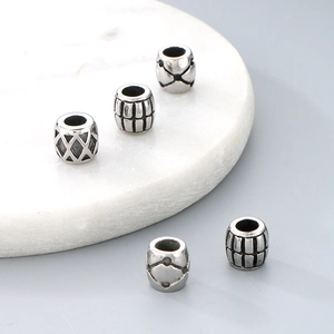 Detailed close-up of patterned titanium steel cylinder beads for DIY jewelry making