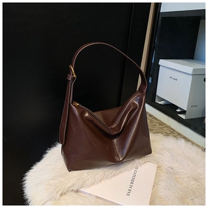 Detailed view of dark brown faux leather hobo bag with glossy finish on plush white rug