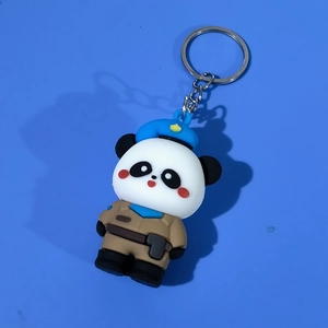 Detailed top view of a cute panda keychain with blue beret on plain blue background
