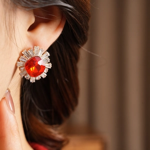 Close-up of vintage gold earring with large red square crystal and halo of clear stones